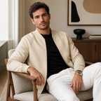 Khaki lightweight bomber jacket worn seated indoors in a relaxed lifestyle pose.