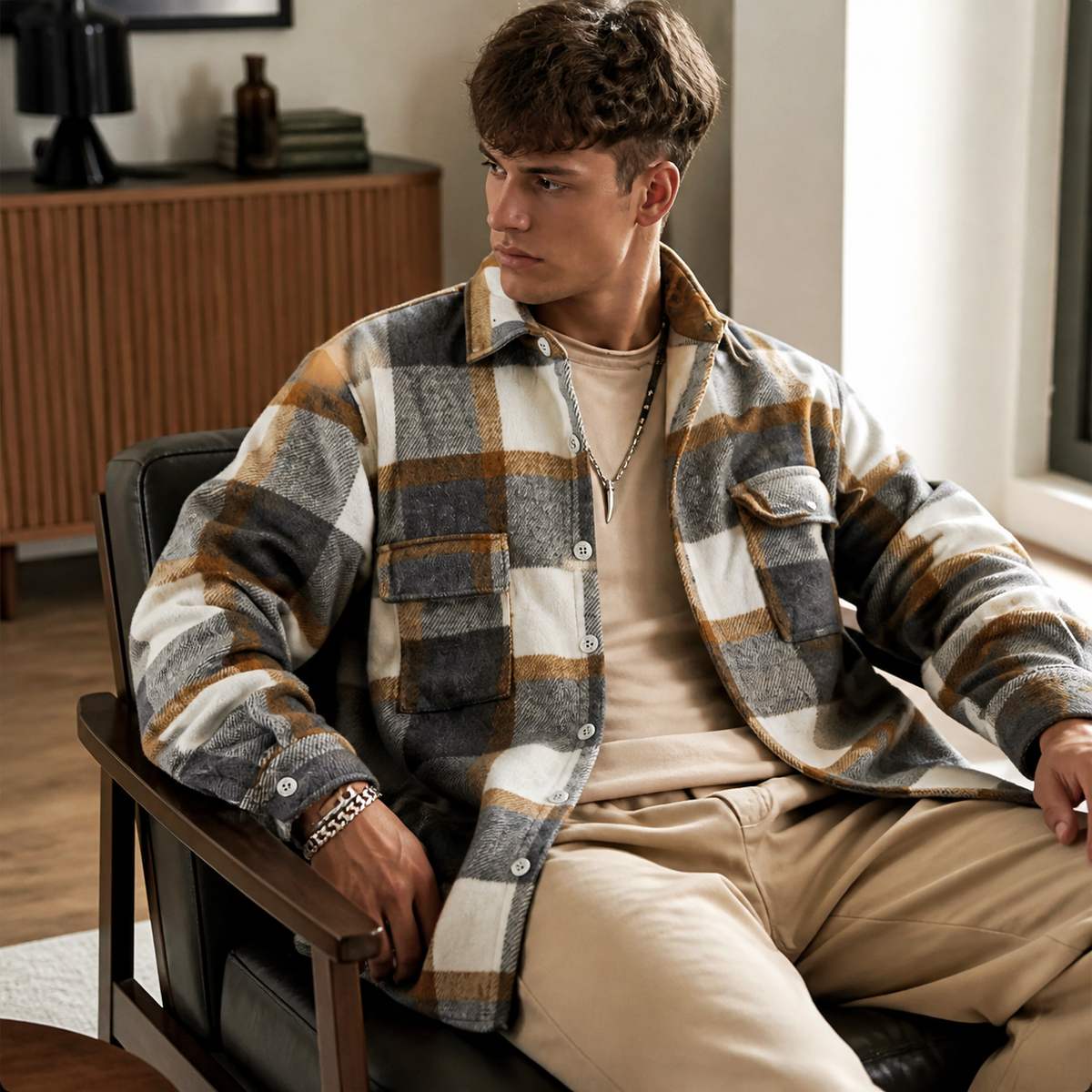 Mixed color plaid overshirt jacket worn seated indoors in a relaxed lifestyle pose.