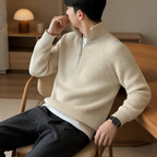 Beige thick ribbed quarter zip sweater worn seated indoors in a relaxed lifestyle pose.