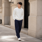 Ivory white ribbed crew neck sweater worn outdoors in a walking lifestyle pose.