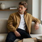 Khaki stand collar bomber jacket worn seated indoors in a relaxed lifestyle pose.