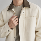 Close-up of the off white work trucker jacket contrast collar, zip and snap front.