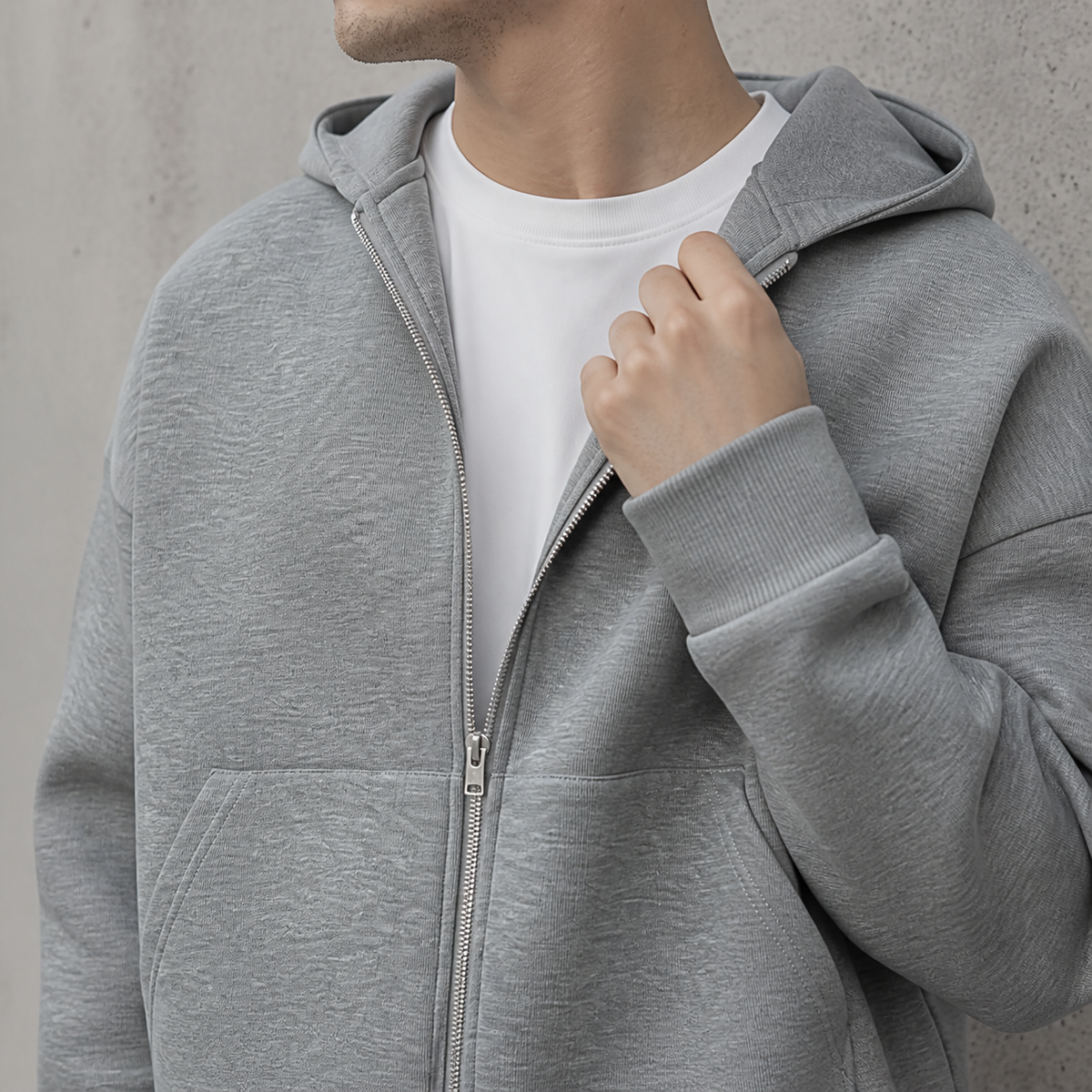 Close-up of the light grey zip up hoodie zipper, hood and soft jersey texture.
