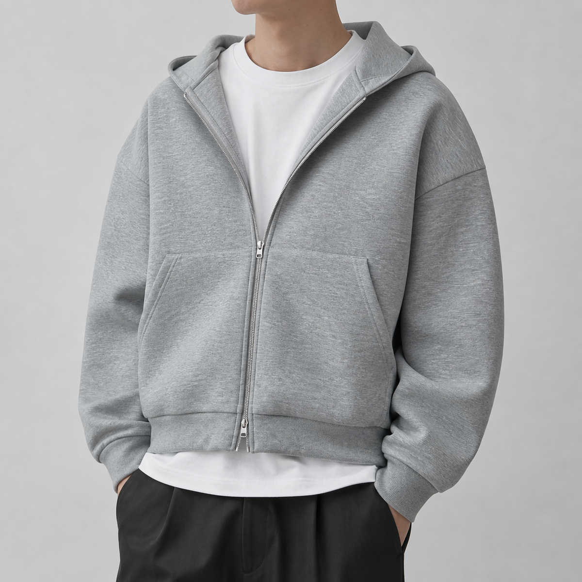 Light grey drop shoulder zip up hoodie on a male model in a clean studio.